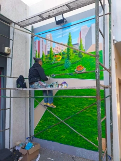 Sergio Caffarena pintando un mural en un andamio